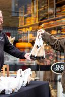 Lachende man verkoopt producten bij kaasboer