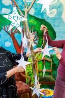 Twee personen houden papieren kunststerren vast bij Sedna Herstelacademie