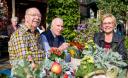 Drie ouderen zitten samen buiten met mooie bloemstukken voor zich